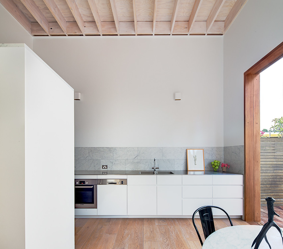 Aménagement d'une cuisine ouverte moderne avec un placard à porte plane, des portes de placard blanches et parquet clair.