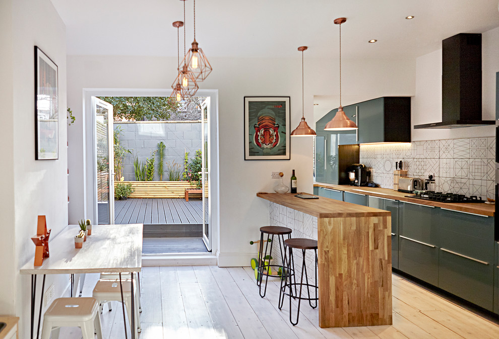 Cette photo montre une cuisine américaine parallèle tendance de taille moyenne avec un placard à porte plane, des portes de placards vertess, un plan de travail en bois, parquet clair, un sol blanc et une péninsule.