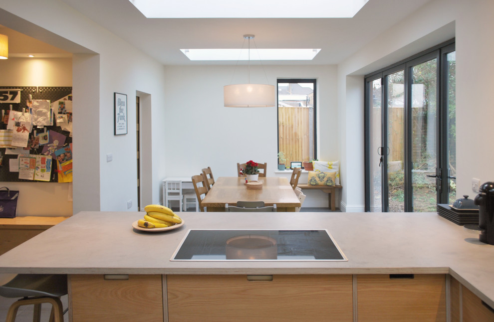 Design ideas for a medium sized retro u-shaped open plan kitchen in Other with a built-in sink, flat-panel cabinets, yellow cabinets, concrete worktops, stainless steel appliances, ceramic flooring, a breakfast bar, grey floors and grey worktops.