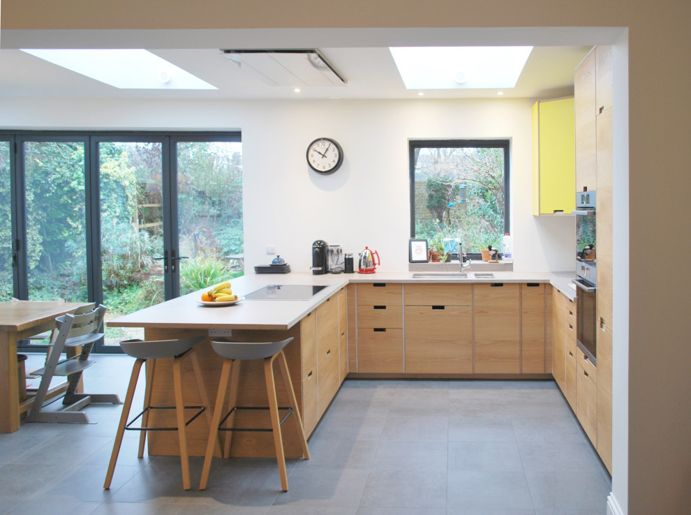 Inspiration for a medium sized retro u-shaped open plan kitchen in Other with a built-in sink, flat-panel cabinets, concrete worktops, stainless steel appliances, ceramic flooring, a breakfast bar, grey floors, grey worktops and yellow cabinets.