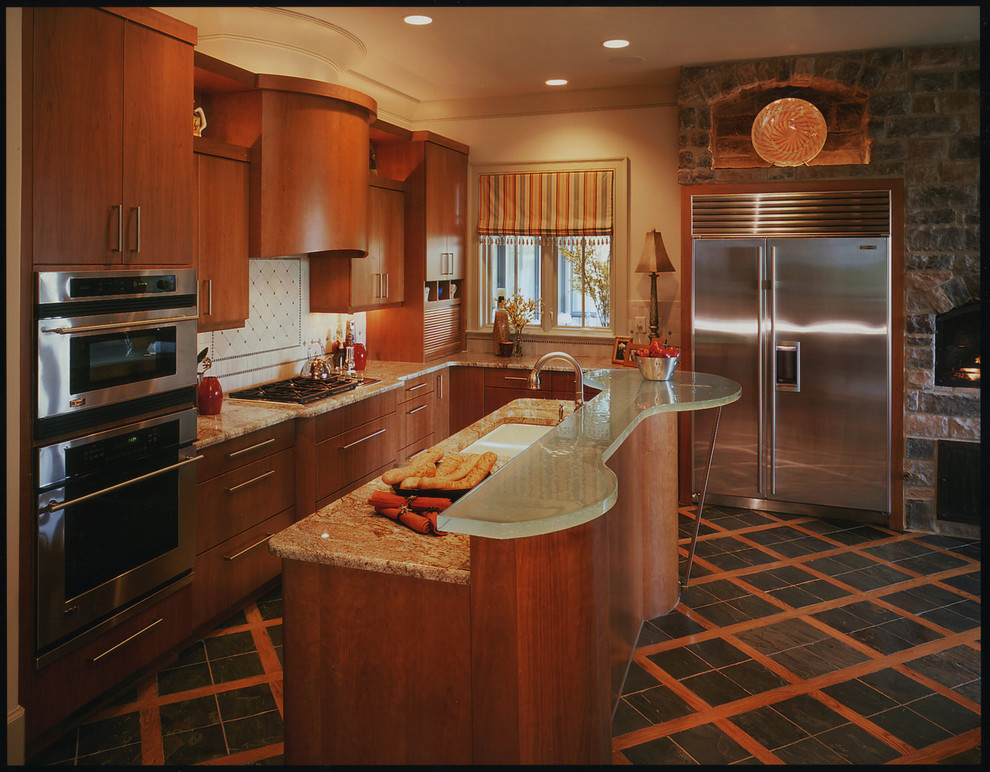 Moderne Küche mit flächenbündigen Schrankfronten, hellbraunen Holzschränken, Granit-Arbeitsplatte, Küchengeräten aus Edelstahl, Kücheninsel und Doppelwaschbecken in Nashville
