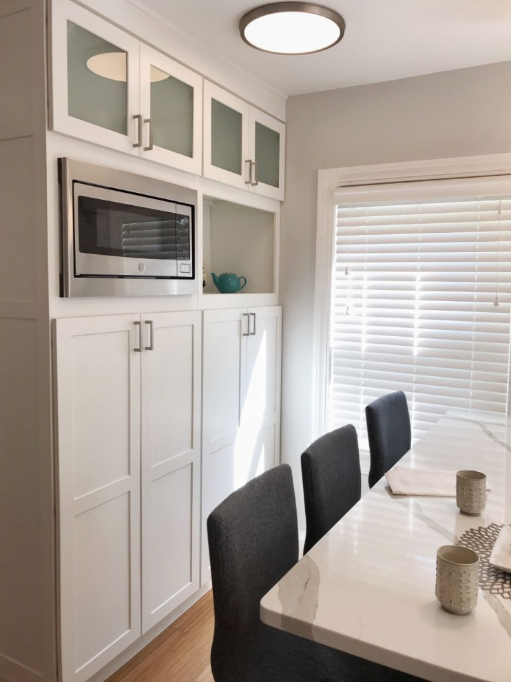 Mid-sized minimalist u-shaped bamboo floor enclosed kitchen photo in Providence with an undermount sink, shaker cabinets, white cabinets, quartz countertops, multicolored backsplash, mosaic tile backsplash, stainless steel appliances, an island and white countertops