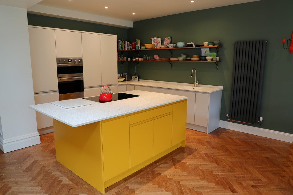 Inspiration for a medium sized contemporary l-shaped open plan kitchen in Other with an integrated sink, flat-panel cabinets, yellow cabinets, composite countertops, stainless steel appliances, an island and white worktops.