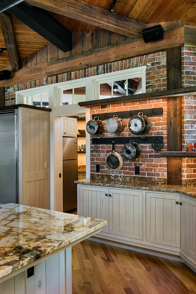 Einzeilige, Mittelgroße Industrial Küche mit Vorratsschrank, profilierten Schrankfronten, beigen Schränken, Küchengeräten aus Edelstahl, braunem Holzboden und Kücheninsel in Boston
