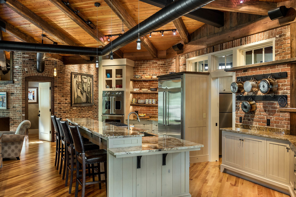 Rustikale Küche in L-Form mit Unterbauwaschbecken, Schrankfronten mit vertiefter Füllung, beigen Schränken, Küchengeräten aus Edelstahl, braunem Holzboden und Kücheninsel in Boston