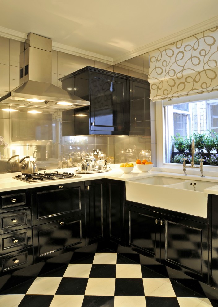 ロンドンにあるトランジショナルスタイルのおしゃれなキッチン (エプロンフロントシンク、黒いキャビネット、ミラータイルのキッチンパネル、シルバーの調理設備、大理石の床) の写真