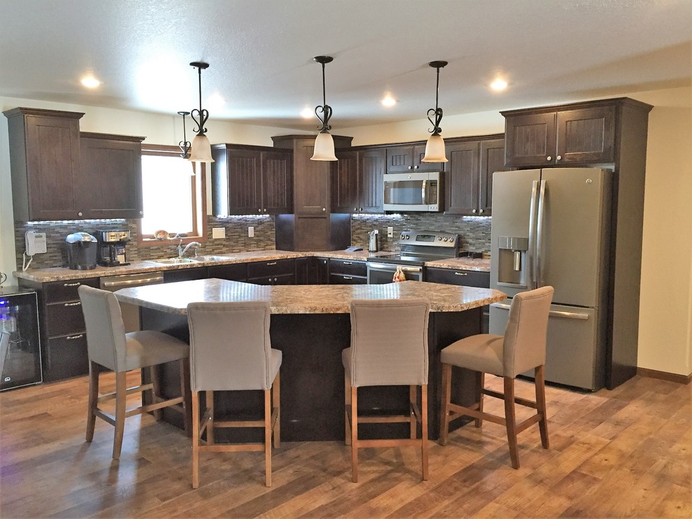 Open concept kitchen - transitional l-shaped medium tone wood floor and brown floor open concept kitchen idea in Other with a drop-in sink, flat-panel cabinets, dark wood cabinets, laminate countertops, multicolored backsplash, mosaic tile backsplash, stainless steel appliances and an island
