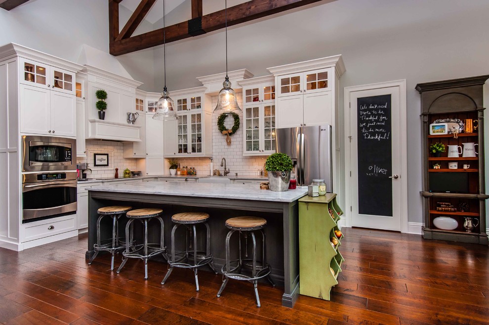 Klassische Küche in L-Form mit Landhausspüle, Glasfronten, weißen Schränken, Küchenrückwand in Weiß, Rückwand aus Metrofliesen und Küchengeräten aus Edelstahl in Orlando