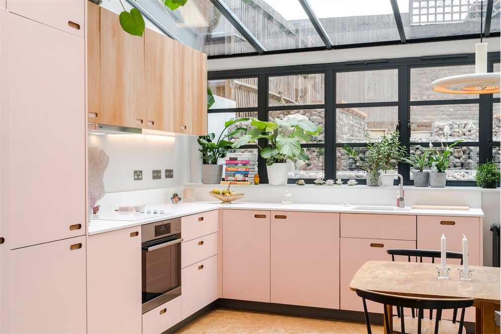 Moderne Wohnküche ohne Insel in L-Form mit Unterbauwaschbecken, flächenbündigen Schrankfronten, Küchengeräten aus Edelstahl, braunem Boden und weißer Arbeitsplatte in London