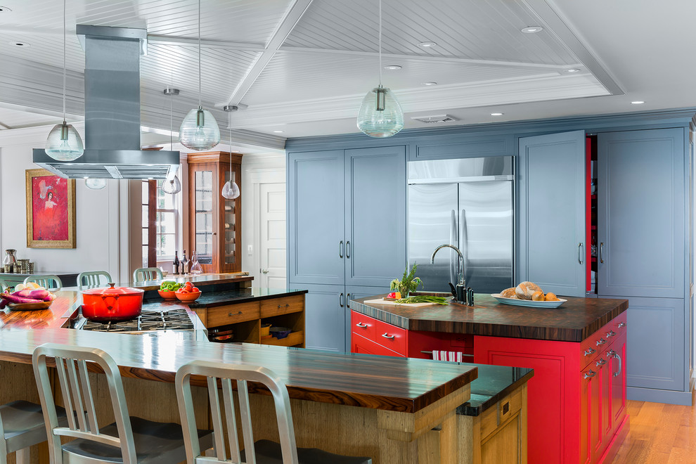Modelo de cocina contemporánea grande con encimera de madera, electrodomésticos de acero inoxidable, suelo de madera en tonos medios, dos o más islas y puertas de armario azules