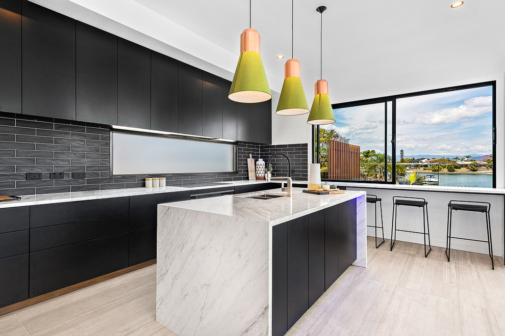 Photo of a large contemporary single-wall kitchen/diner in Brisbane with a submerged sink, flat-panel cabinets, black cabinets, black splashback, metro tiled splashback, an island, beige floors, granite worktops, stainless steel appliances and porcelain flooring.