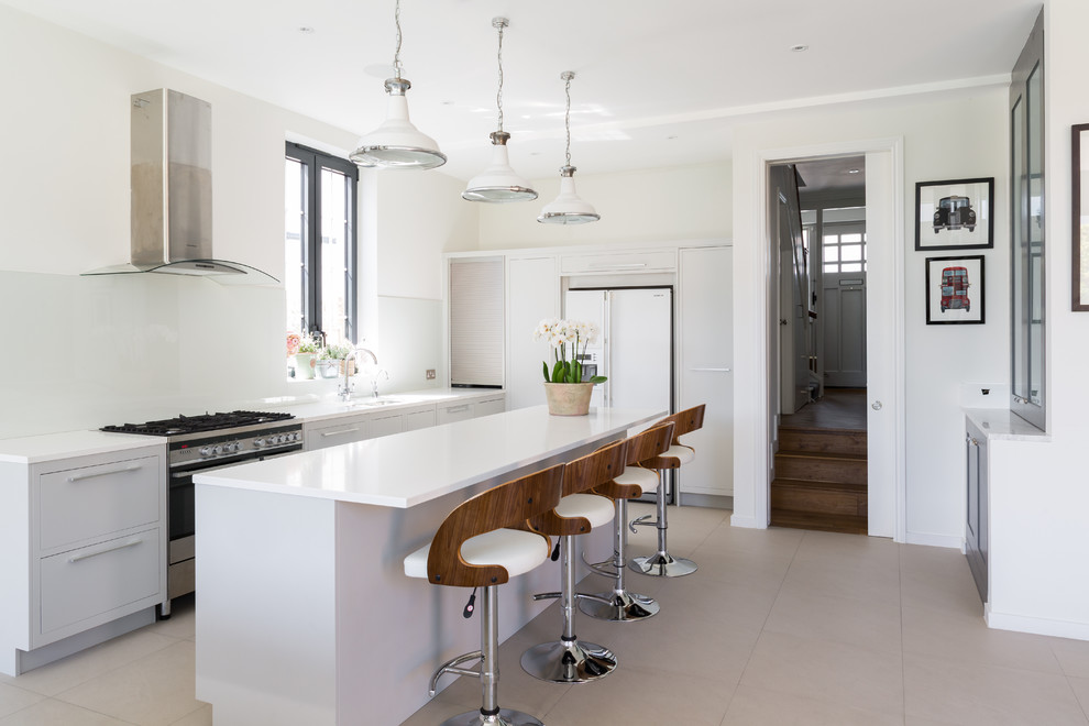 Foto de cocina comedor actual grande con fregadero integrado, armarios con paneles lisos, puertas de armario grises, encimera de acrílico, salpicadero de vidrio templado, electrodomésticos de acero inoxidable, suelo de baldosas de porcelana y una isla