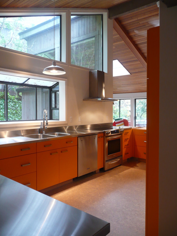 Bild på ett retro kök, med en integrerad diskho, släta luckor, orange skåp och bänkskiva i rostfritt stål