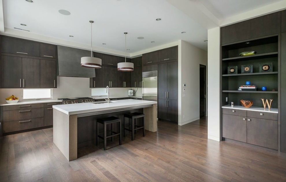 Photo of a medium sized contemporary l-shaped open plan kitchen in Seattle with a double-bowl sink, flat-panel cabinets, dark wood cabinets, quartz worktops, white splashback, stainless steel appliances, an island, stone slab splashback and dark hardwood flooring.