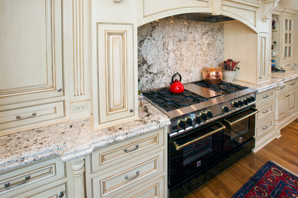 Offene, Große Klassische Küche in L-Form mit profilierten Schrankfronten, beigen Schränken, Granit-Arbeitsplatte, bunter Rückwand, Rückwand aus Stein und Kücheninsel in Denver
