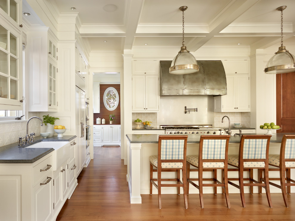 Example of a classic kitchen design in Seattle with a farmhouse sink, raised-panel cabinets, white cabinets, white backsplash and stainless steel appliances