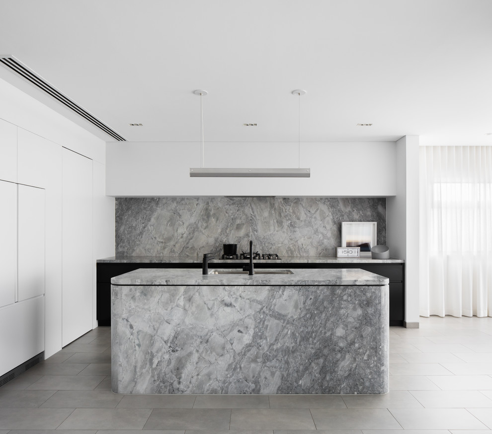 Cette image montre une cuisine encastrable et grise et blanche minimaliste en L avec un évier encastré, un placard à porte plane, une crédence grise, une crédence en marbre, îlot, un sol gris et un plan de travail gris.