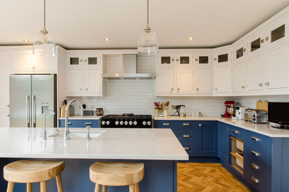 Design ideas for a large rural l-shaped kitchen/diner in Kent with an integrated sink, shaker cabinets, blue cabinets, quartz worktops, metro tiled splashback, coloured appliances, medium hardwood flooring and an island.