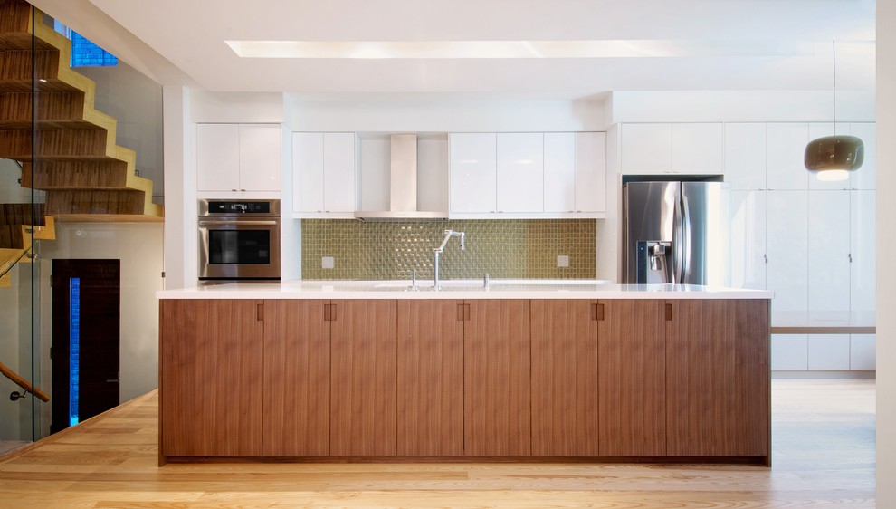 Inspiration för stora moderna linjära vitt kök med öppen planlösning, med en undermonterad diskho, släta luckor, vita skåp, rostfria vitvaror, ljust trägolv, en köksö och brunt golv