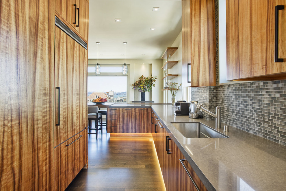 Kitchen - contemporary galley medium tone wood floor kitchen idea in San Francisco with an undermount sink, flat-panel cabinets, medium tone wood cabinets, multicolored backsplash, mosaic tile backsplash, paneled appliances and a peninsula