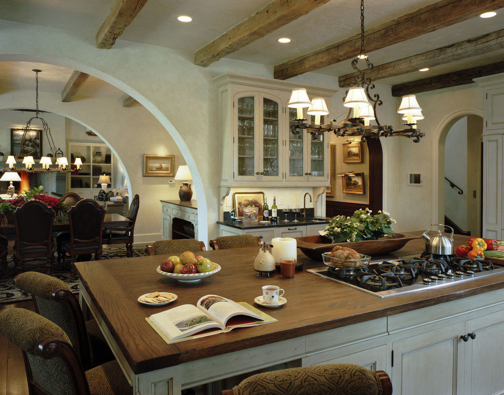 Foto på ett rustikt kök med öppen planlösning, med luckor med glaspanel, vita skåp och träbänkskiva