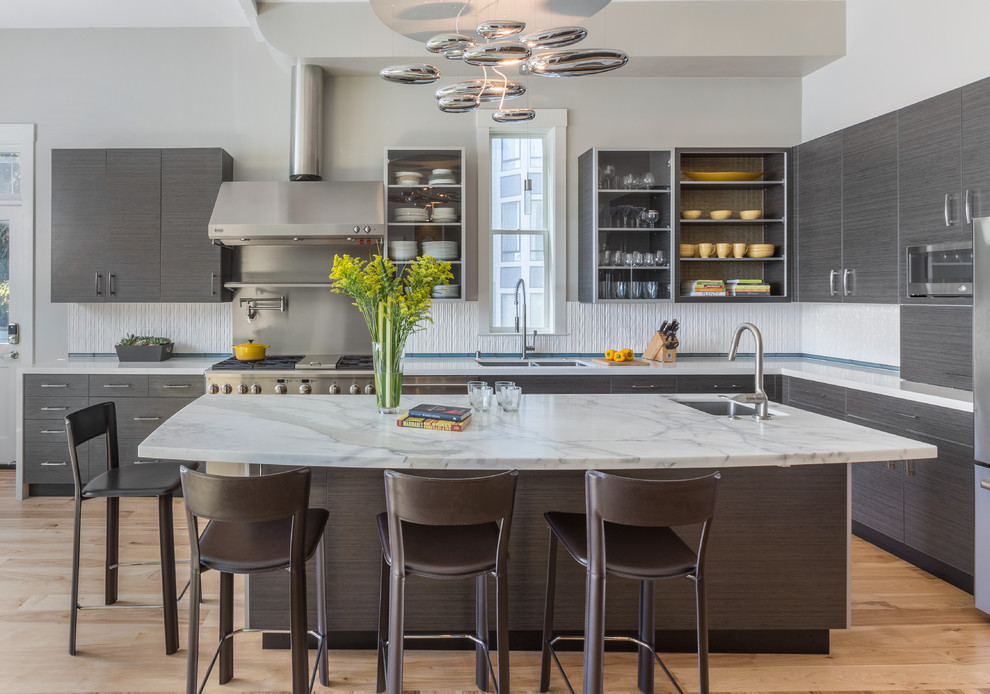 Enclosed kitchen - large contemporary u-shaped medium tone wood floor enclosed kitchen idea in San Francisco with flat-panel cabinets, gray cabinets, marble countertops, white backsplash, ceramic backsplash, stainless steel appliances, an island and a double-bowl sink
