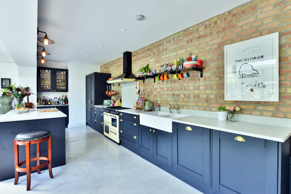 Foto på ett eklektiskt kök, med en rustik diskho, skåp i shakerstil, svarta skåp, granitbänkskiva, brunt stänkskydd, stänkskydd i tegel, färgglada vitvaror, betonggolv, en köksö och grått golv