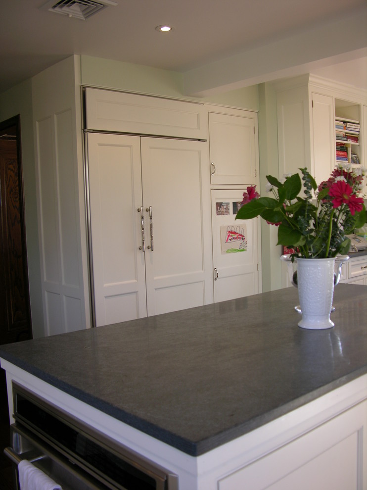 Example of a mid-sized classic l-shaped eat-in kitchen design in New York with beaded inset cabinets, white cabinets, soapstone countertops, paneled appliances and an island