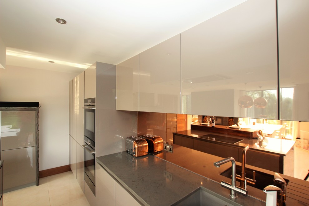 Ispirazione per un cucina con isola centrale design con ante di vetro, ante grigie, top in quarzite, paraspruzzi a effetto metallico e paraspruzzi a specchio
