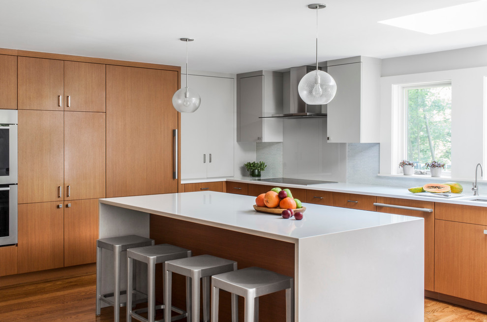 Inspiration for a modern u-shaped eat-in kitchen remodel in Boston with an undermount sink, flat-panel cabinets, medium tone wood cabinets, blue backsplash, glass tile backsplash and paneled appliances