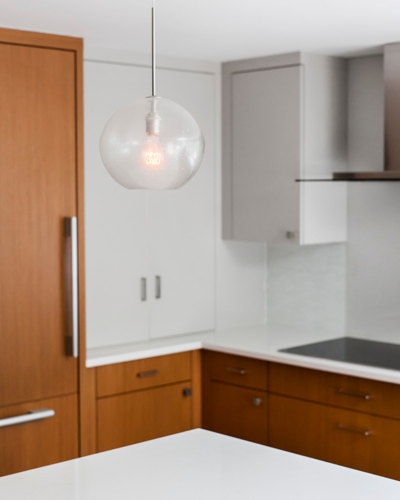 Minimalist u-shaped eat-in kitchen photo in Boston with an undermount sink, flat-panel cabinets, medium tone wood cabinets, blue backsplash, glass tile backsplash and paneled appliances