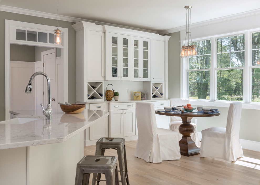 Inspiration for a farmhouse kitchen/diner in Providence with a belfast sink, shaker cabinets, white cabinets, light hardwood flooring and an island.