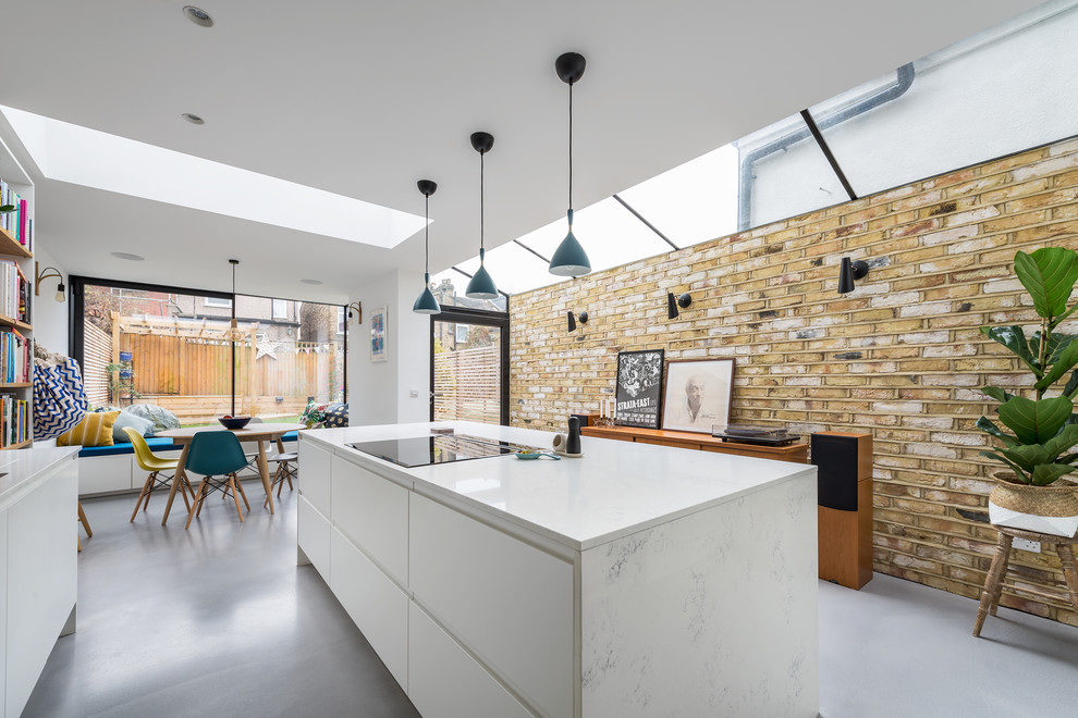Inspiration for a medium sized contemporary kitchen/diner in London with an integrated sink, flat-panel cabinets, white cabinets, quartz worktops, white splashback, brick splashback, stainless steel appliances, concrete flooring, an island and grey floors.