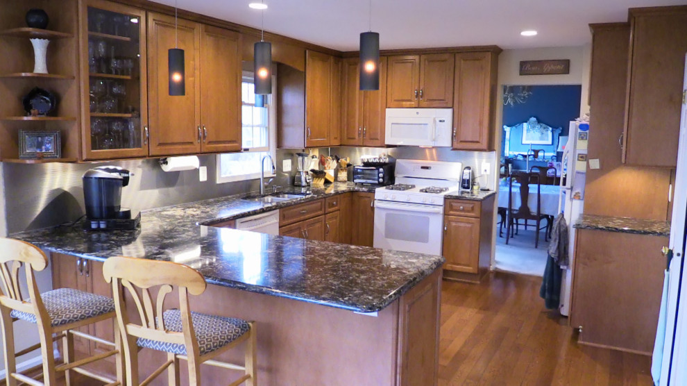 Idéer för att renovera ett avskilt, mellanstort funkis svart svart u-kök, med en dubbel diskho, luckor med upphöjd panel, skåp i mellenmörkt trä, bänkskiva i kvarts, stänkskydd med metallisk yta, vita vitvaror, mellanmörkt trägolv, en halv köksö och brunt golv