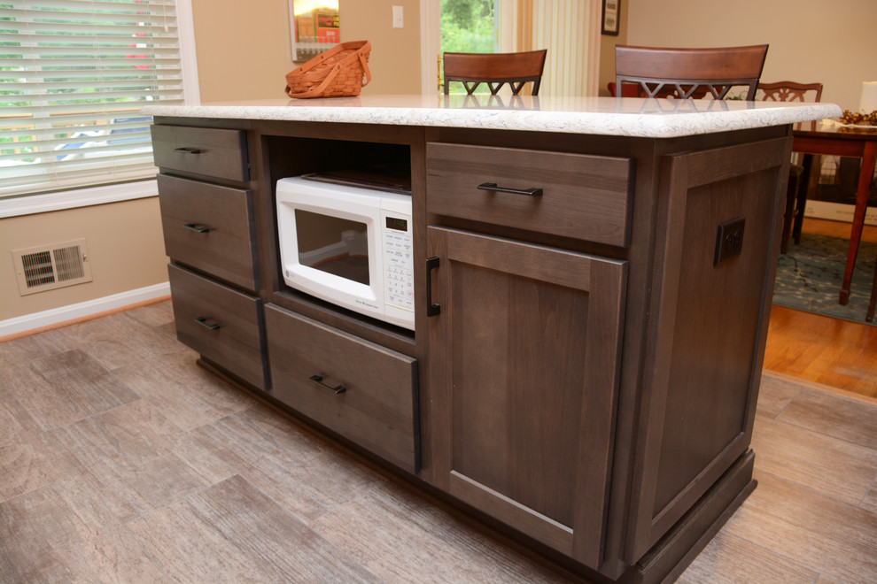 Small traditional l-shaped kitchen pantry in DC Metro with a submerged sink, recessed-panel cabinets, dark wood cabinets, engineered stone countertops, beige splashback, porcelain splashback, stainless steel appliances and an island.