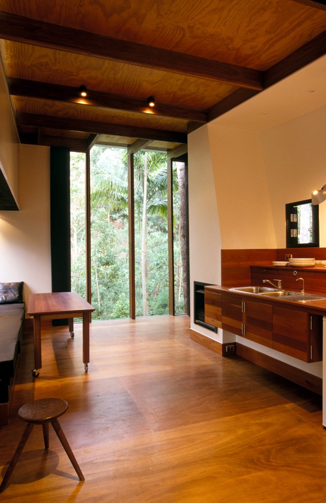 Foto di una cucina lineare tropicale di medie dimensioni con lavello a doppia vasca, ante in legno bruno, top in legno e pavimento in compensato