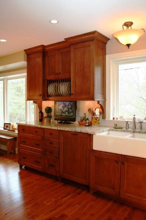 Example of a mid-sized classic l-shaped medium tone wood floor eat-in kitchen design in Milwaukee with a farmhouse sink, raised-panel cabinets, dark wood cabinets, granite countertops, white backsplash, ceramic backsplash, stainless steel appliances and an island