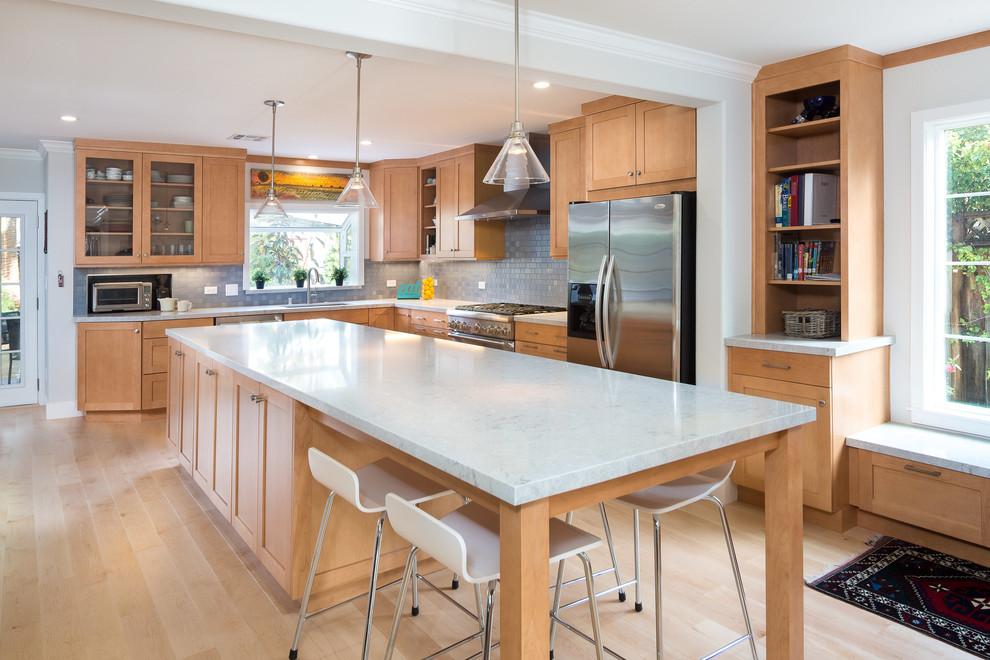 Foto på ett vintage l-kök, med en undermonterad diskho, skåp i shakerstil, skåp i ljust trä, blått stänkskydd, rostfria vitvaror, ljust trägolv, en köksö och beiget golv