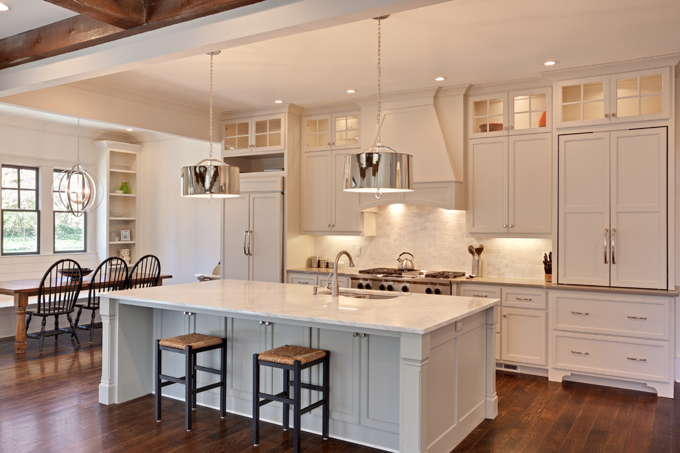 Open concept kitchen - mid-sized traditional single-wall medium tone wood floor open concept kitchen idea in Atlanta with an undermount sink, recessed-panel cabinets, white cabinets, marble countertops, multicolored backsplash, stone tile backsplash, paneled appliances and an island