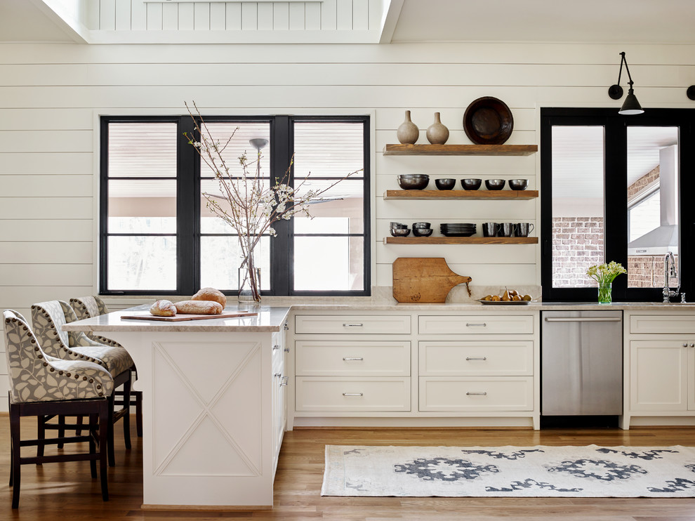 Example of a mid-sized country medium tone wood floor and brown floor kitchen design in Atlanta with white cabinets, stainless steel appliances, a peninsula, an undermount sink, marble countertops, white backsplash, white countertops and beaded inset cabinets