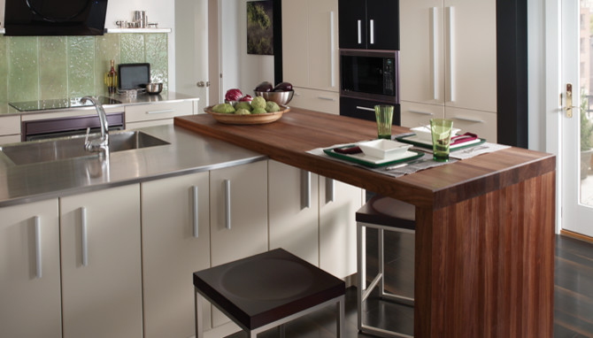 Foto på ett litet funkis kök, med en integrerad diskho, släta luckor, vita skåp, bänkskiva i rostfritt stål, grönt stänkskydd, stänkskydd i glaskakel, svarta vitvaror, mörkt trägolv och en köksö
