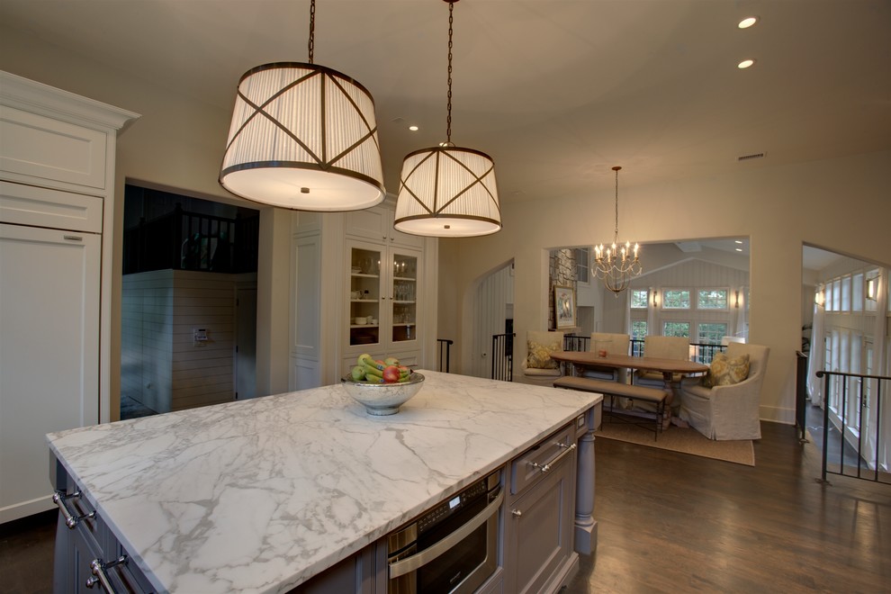 Immagine di una cucina chic di medie dimensioni con lavello sottopiano, ante a filo, ante bianche, top in marmo, elettrodomestici da incasso, parquet scuro e pavimento marrone
