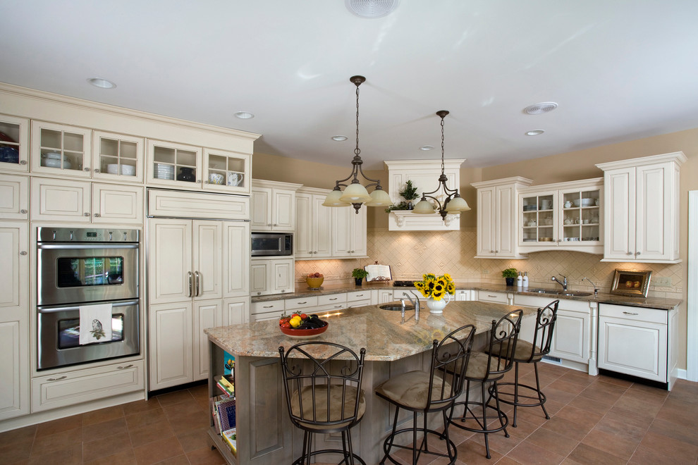 Kitchen - large traditional l-shaped ceramic tile kitchen idea in Chicago with an undermount sink, raised-panel cabinets, white cabinets, granite countertops, beige backsplash, ceramic backsplash, paneled appliances and an island