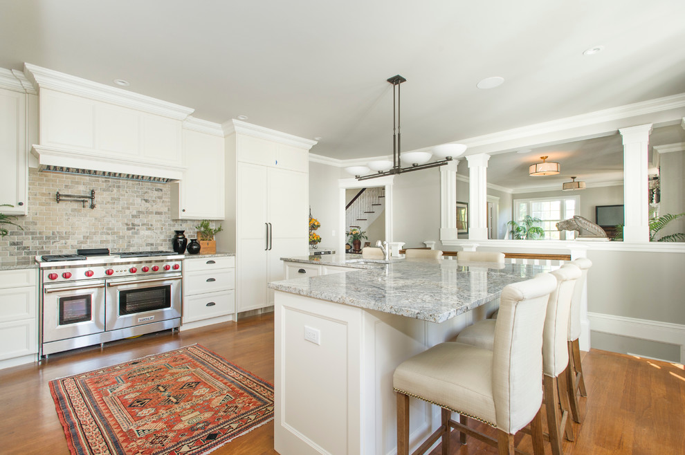 Photo of a traditional u-shaped kitchen in Boston with a submerged sink, recessed-panel cabinets, white cabinets, grey splashback, stainless steel appliances, medium hardwood flooring and an island.