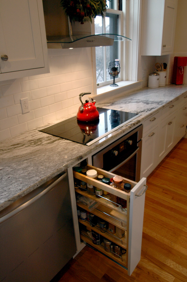 Inspiration for a contemporary single-wall eat-in kitchen remodel in Boston with an undermount sink, shaker cabinets, white cabinets, granite countertops, white backsplash, ceramic backsplash and white appliances