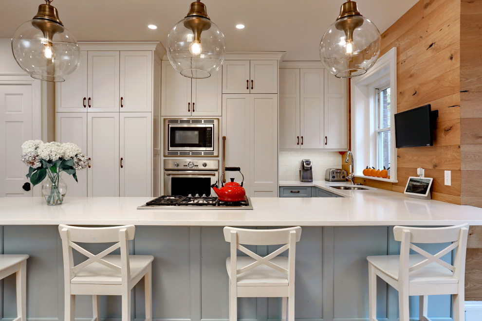 Foto på ett mellanstort lantligt vit kök, med en undermonterad diskho, luckor med infälld panel, vita skåp, bänkskiva i kvarts, vitt stänkskydd, stänkskydd i keramik, integrerade vitvaror, mellanmörkt trägolv, en halv köksö och brunt golv