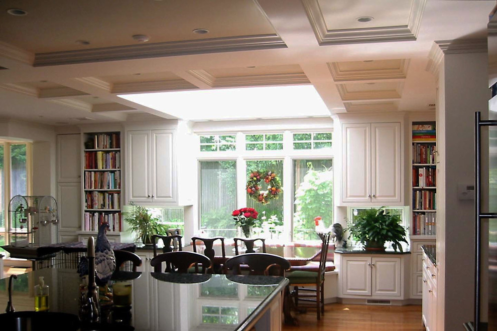 Inredning av ett klassiskt stort kök, med luckor med upphöjd panel, vita skåp, granitbänkskiva, en köksö, en undermonterad diskho, stänkskydd i keramik, rostfria vitvaror, mellanmörkt trägolv och brunt golv