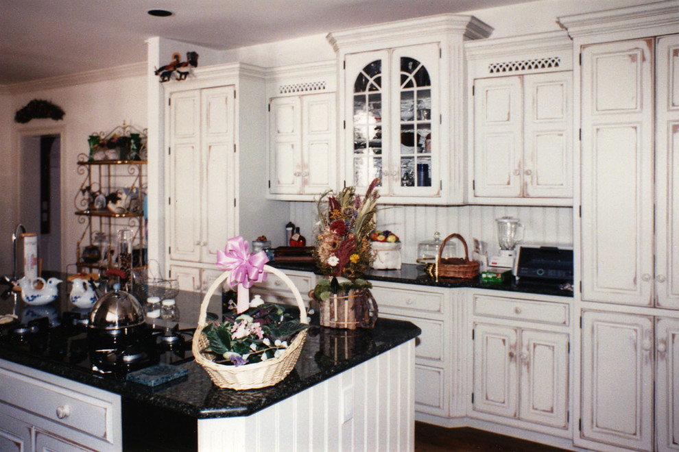 Large traditional l-shaped kitchen/diner in Boston with a submerged sink, raised-panel cabinets, distressed cabinets, granite worktops, medium hardwood flooring, an island and brown floors.