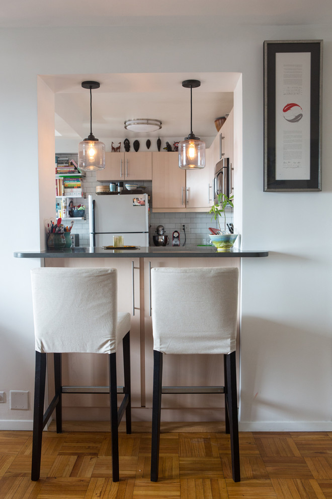 На фото: отдельная, п-образная кухня в стиле неоклассика (современная классика) с плоскими фасадами, светлыми деревянными фасадами, белым фартуком, фартуком из плитки кабанчик и белой техникой с