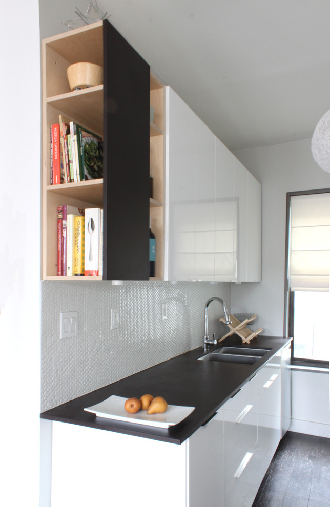 На фото: глянцевая кухня в стиле модернизм с двойной мойкой, плоскими фасадами, белым фартуком и черно-белыми фасадами с